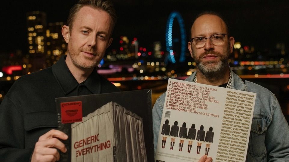 Chase & Status hold a vinyl copy of their album Generic Everything in front of the London skyline